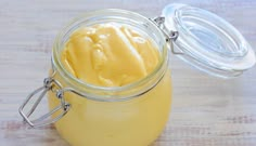 a jar filled with yellow liquid sitting on top of a wooden table