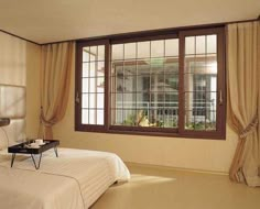 a bedroom with a large bed and two windows that look out onto the yard outside