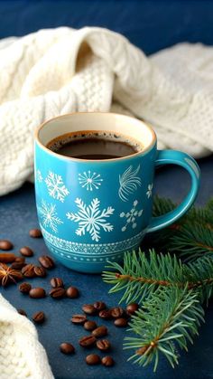 a cup of hot chocolate and some coffee beans on a blue table with white knits