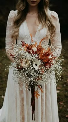 a woman in a white dress holding a bouquet of orange and white flowers on her wedding day