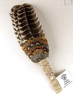 a feathered bird toy with a tag attached to it's side on a white surface