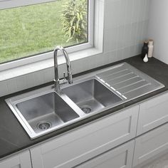 a kitchen sink with two faucets in front of it and a window behind it