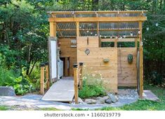 a small wooden structure in the middle of some grass and trees, with a walkway leading to it