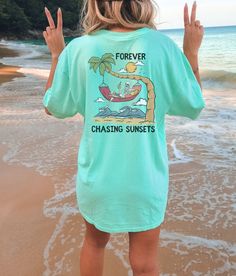 "These cute beachy, distressed tees make a perfect beach coverup or lounge tee! Or mix and match colors with friends for a perfect group vacation photo! Please note that this design comes in black ink only, and is only on the back of the tshirt! About Comfort Colors Tees! (Unisex Shirts!) These ultra soft pigment dyed shirts are one of our best sellers ⭐️ 100% ring spun cotton ⭐️ PRESHRUNK, soft-washed, garment-dyed fabric ⭐️ Set-in sleeves ⭐️ Double-needle stitched sleeves and bottom hem ⭐️ Twi Casual Crew Neck T-shirt For Vacation, Relaxed Summer Loungewear T-shirt, Relaxed Summer T-shirt For Loungewear, Casual Short Sleeve T-shirt For Beach Season, Relaxed Short Sleeve T-shirt For Vacation, Oversized Casual T-shirt For Beach Season, Green Letter Print T-shirt For Vacation, Relaxed Summer Vacation Top, Trendy Green T-shirt For Vacation