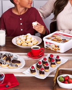 two people sitting at a table with desserts and milk in front of them on plates