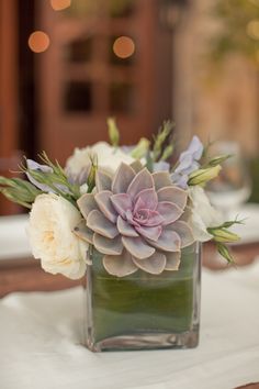 a square vase filled with flowers on top of a table