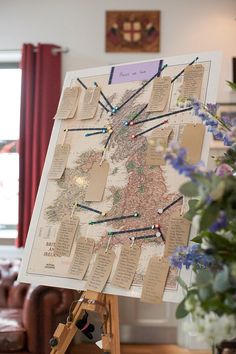 the wedding map is displayed on an easel in front of a flower vase and window