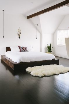 an instagram photo of a bed in a bedroom with white walls and wood floors