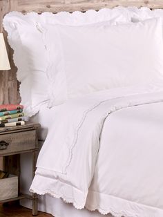 a bed with white sheets and pillows on top of it next to a night stand