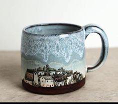 a ceramic mug with a city scene painted on it