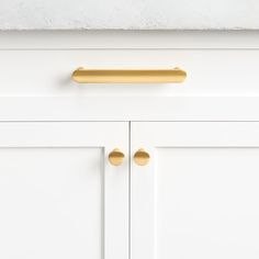 a white cabinet with gold handles and knobs