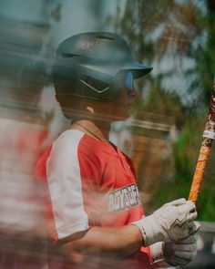 a man holding a baseball bat in his hands and wearing a helmet on top of it