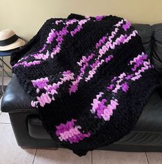 a crocheted blanket sitting on top of a black couch