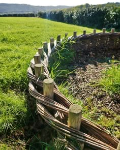 a wooden fence in the middle of a grassy field