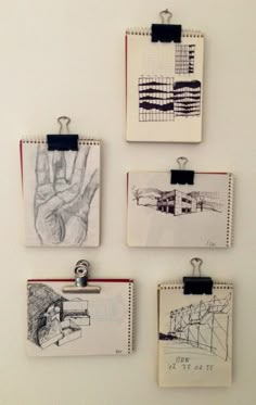 four drawings are hanging on the wall with clipboards attached to each one's sides