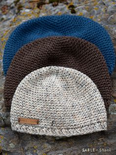 three knitted hats sitting on top of a rock