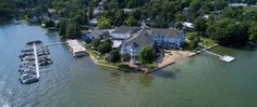 an aerial view of a house on the water with boats parked in front of it