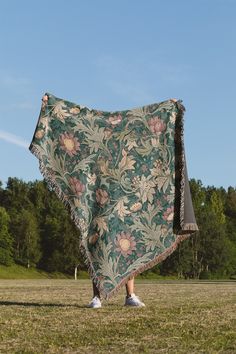 a person standing in a field holding up a blanket