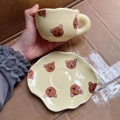 someone is holding two cups and saucers with teddy bears on them, one in the shape of a bear