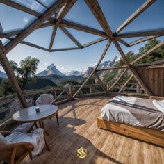 a bed sitting on top of a wooden floor next to a table and two chairs