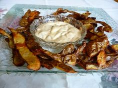 a glass plate topped with potato wedges next to a bowl of dip