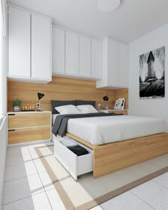 a bed sitting under a window next to white cupboards in a room with tile flooring