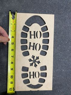 someone is holding a ruler next to a cut out paper with the words ho ho ho on it