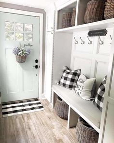 a white entryway with black and white checkered pillows on the bench next to it