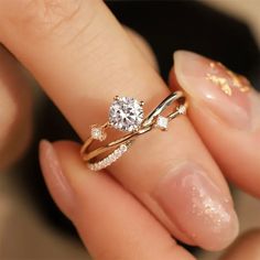 a close up of a person's hand holding a ring with a diamond on it