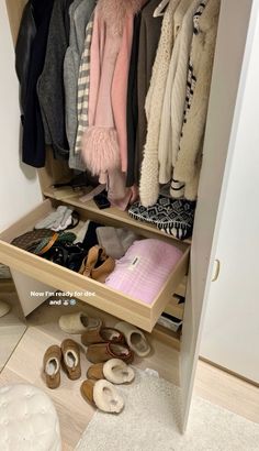 an open closet with shoes and coats on the shelves, next to a pair of slippers