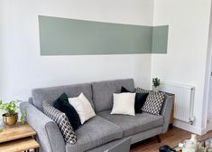 a living room with grey couches and black and white pillows on the back of them