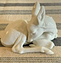 a white ceramic animal laying on top of a rug