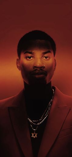 a man in a suit and necklace looking up at the camera with an intense look on his face