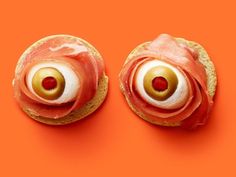 two sandwiches with ham, cheese and olives in the shape of eyeballs on an orange background