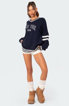 Enjoy Big Apple energy in this varsity sweater designed with dropped shoulders and contrasting stripes. V-neck Long sleeves Ribbed cuffs and hem 100% acrylic Hand wash, dry flat Imported Oversized Sweater With Ribbed Cuffs For Campus, Navy College Sweater, Sporty V-neck Sweatshirt With Ribbed Cuffs, Oversized Varsity Sweater With Ribbed Cuffs, Navy Varsity Top With Ribbed Cuffs, Navy Varsity Tops With Ribbed Cuffs, Varsity Sweater For Game Day In Winter, Oversized Varsity Sweater For Campus, Varsity Sweater With Ribbed Collar For Streetwear