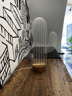 a wire cactus sitting on top of a wooden table next to a white and black wall