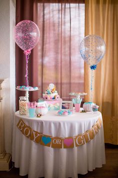 a table with balloons, cake and other items on it in front of a window