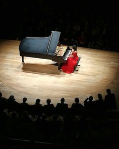 a person sitting at a piano on top of a stage in front of an audience