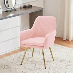 a pink chair sitting on top of a rug in front of a desk with a mirror