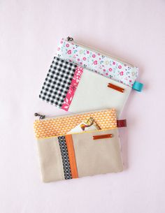 three small zippered pouches on a pink surface