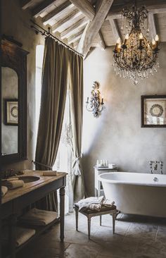 a bathroom with a tub, chandelier and two sinks