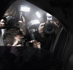 two people taking pictures with their cameras in the back seat of a car at night