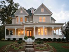 a large white house with lots of windows on the front and side of it's porch