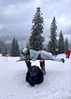 two snowboarders are laying on their back in the snow