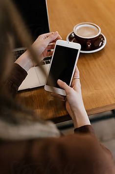 a person sitting at a table with a laptop and cell phone in front of them