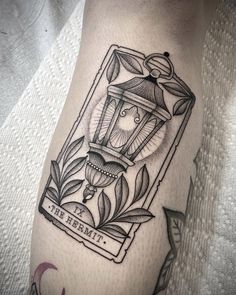 a black and white photo of a lantern tattoo on the leg