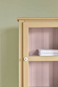 a book shelf with books on top of it next to a green wall and a clock