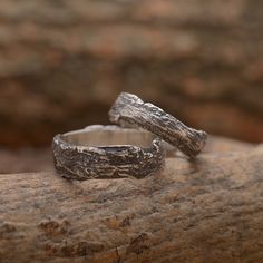 two silver rings sitting on top of a rock