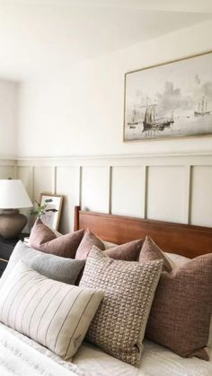 a bed with lots of pillows on it and a painting above the headboard behind it