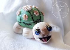 a small turtle figurine with flowers on its shell is smiling for the camera